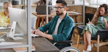 Une homme en fauteuil roulant travaillant dans un bureau Une homme en fauteuil roulant travaillant dans un bureau